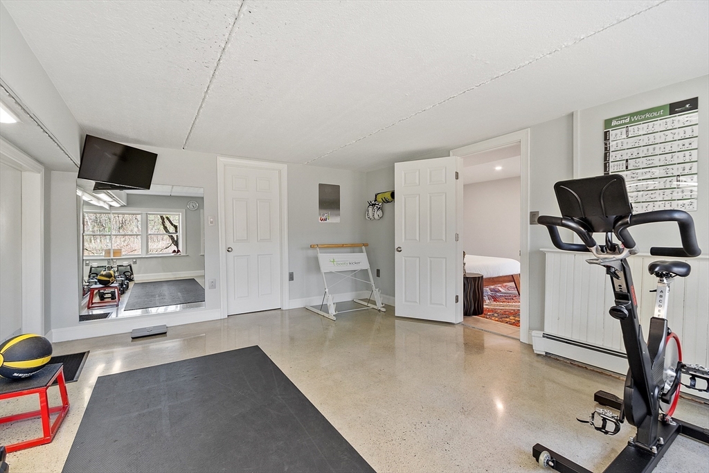4 Willow Road Harvard, MA 01451 - Photo 35 of 42 a living room with furniture a flat screen tv and gym equipment