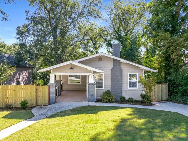 a view of a house with a yard and large tree