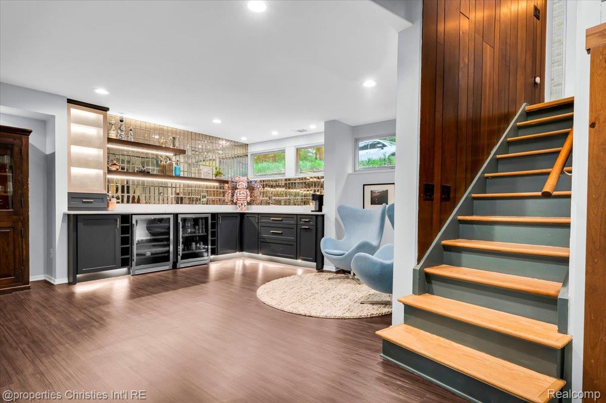 3939 Charing Cross Road Bloomfield Hills, MI 48304 - Photo 28 of 33 Entertainment space featuring wood-finish flooring, a built-in wet bar with under-cabinet lighting, wine refrigerators, and mirrored tile backsplash