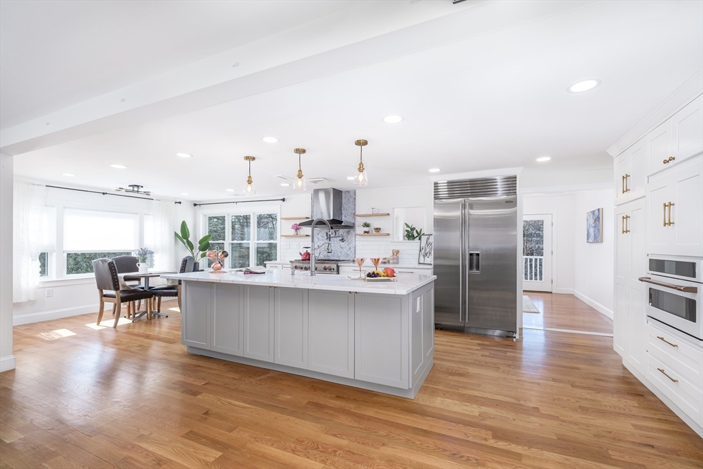 33 Sargent Road Winchester, MA 01890 - Photo 6 of 42 a kitchen with stainless steel appliances a refrigerator a stove top oven and a dining table with wooden floor