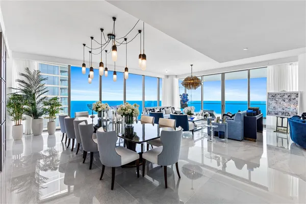 a view of a dining room and livingroom with furniture wooden floor a rug a painting and a chandelier