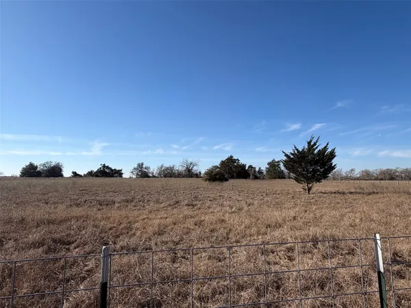 a view of a dry yard with wooden fence