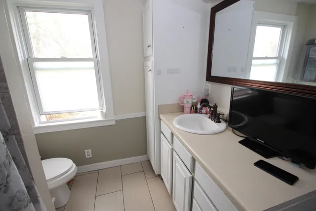 a bathroom with a sink a toilet a window and mirror