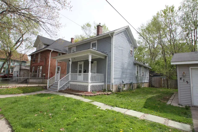 a view of a house with a yard and a large tree