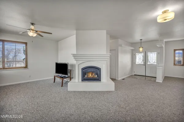 an empty room with chandelier fan and windows