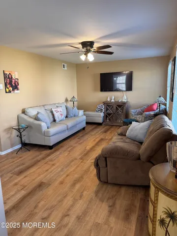 a view of a hallway with wooden floor and a bathroom