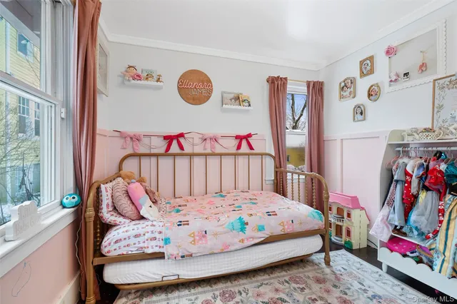 a bedroom with a bed and dresser with wooden floor