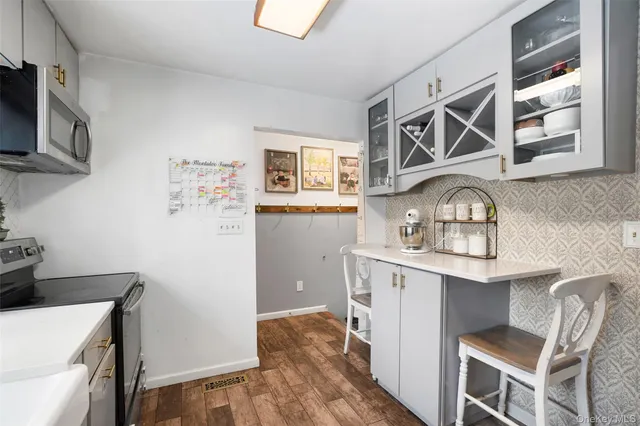 a kitchen with stainless steel appliances a stove top oven a sink a refrigerator wooden floor and cabinets