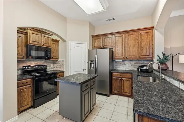 a kitchen with granite countertop a refrigerator stove and sink