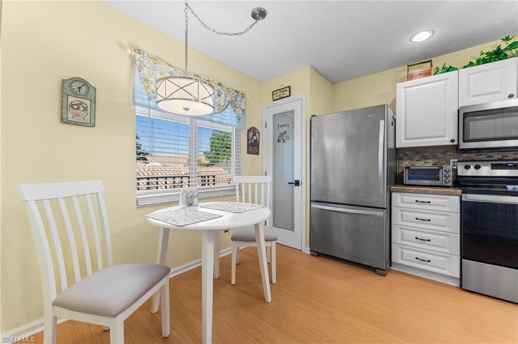 5928 Cranbrook Way, Unit D202 Naples, FL 34112 - Photo 6 of 23 Kitchen featuring white cabinets, light wood-type flooring, appliances with stainless steel finishes, and a toaster