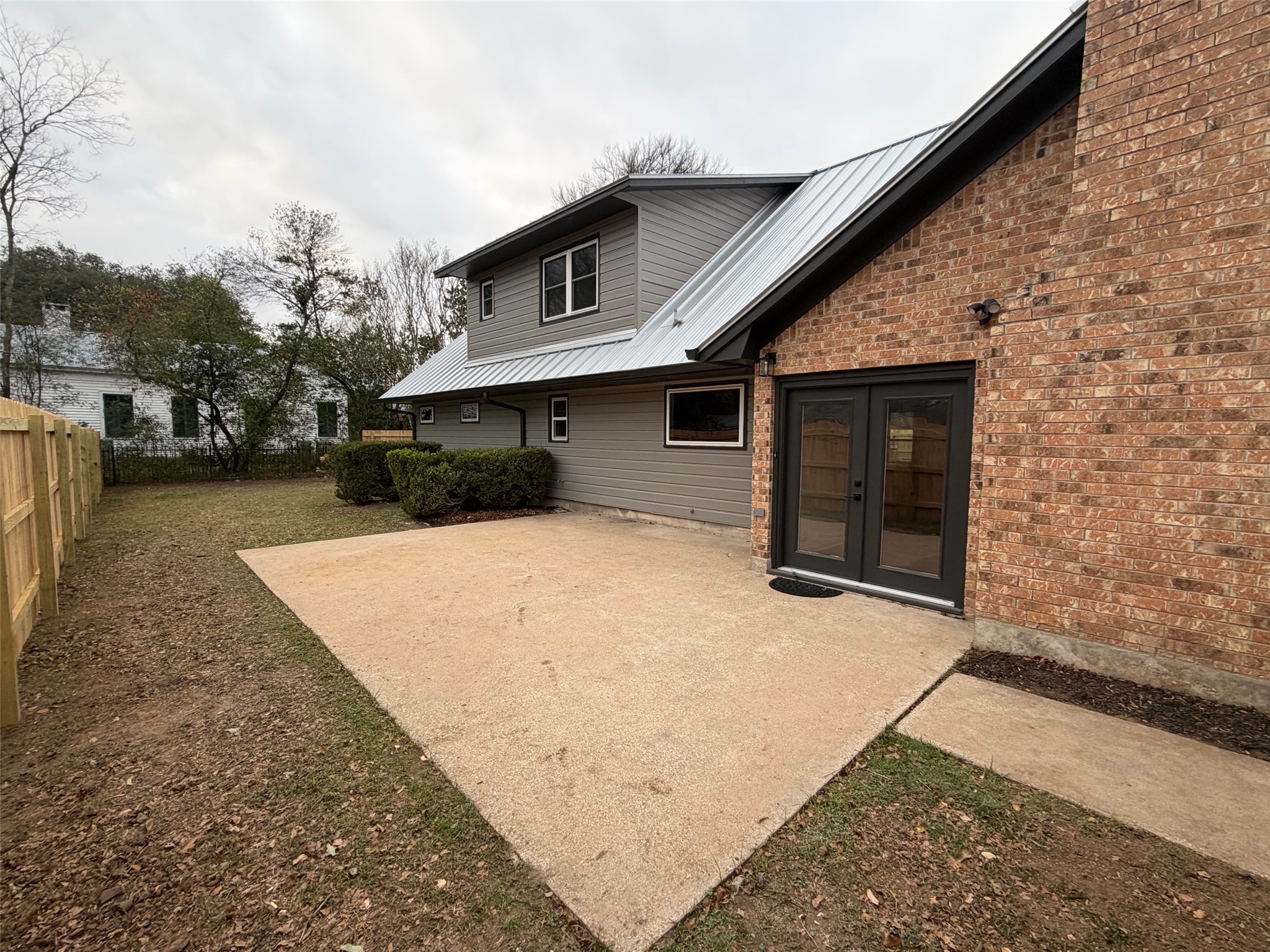 503 Elm Street Bastrop, TX 78602 - Photo 27 of 27 Back of property with a metal roof, a patio area, a fenced backyard, brick siding, and french doors
