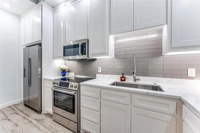 a kitchen with white cabinets and stainless steel appliances