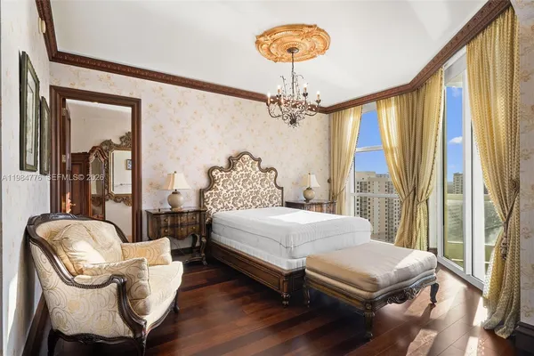 a bedroom with a bed a chandelier and dresser