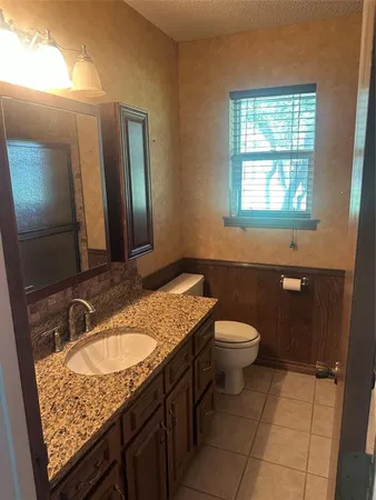 a bathroom with a granite countertop sink toilet and mirror