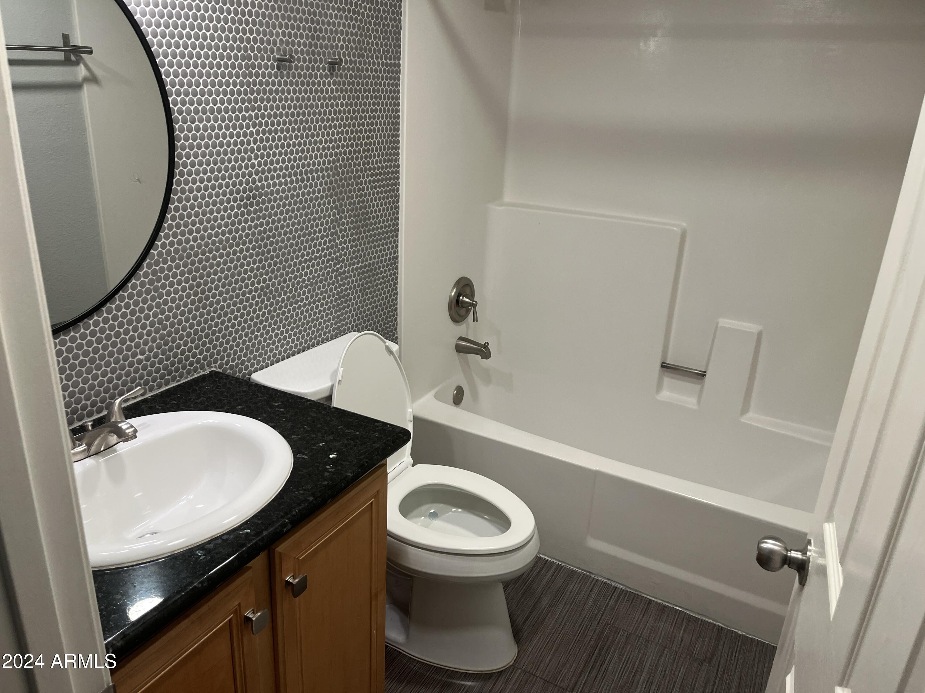 740 West Elm Street, Unit 110 Phoenix, AZ 85013 - Photo 14 of 22 a bathroom with a granite countertop toilet a sink and a mirror