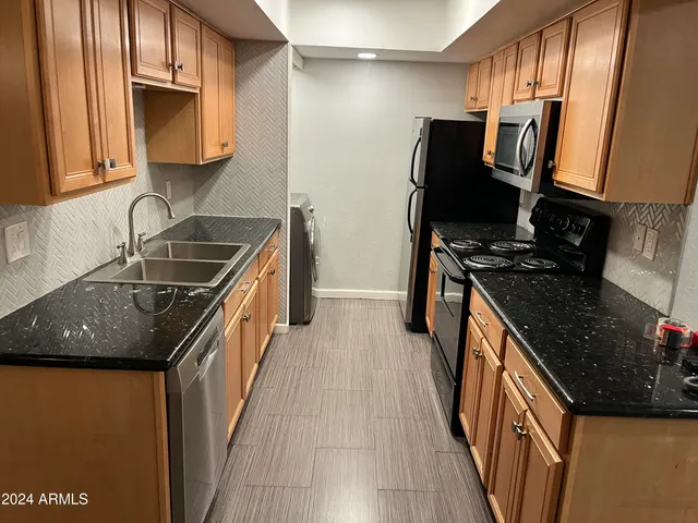 a kitchen with granite countertop a sink stove and refrigerator