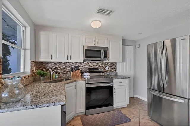 a kitchen with granite countertop a stove sink and refrigerator