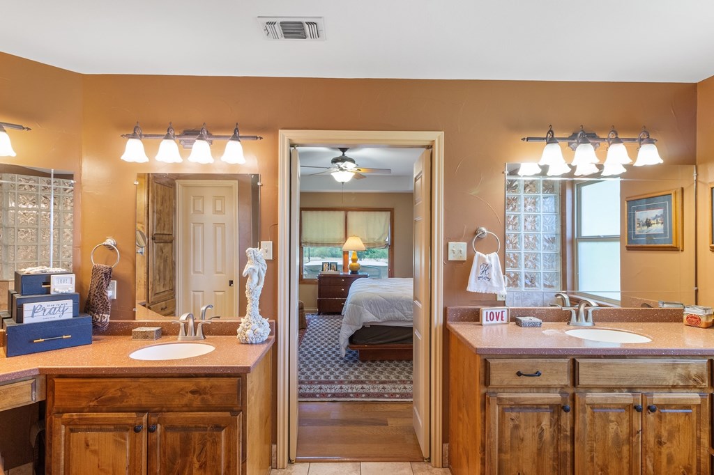647 Funf Kinder Road Fredericksburg, TX 78624 - Photo 49 of 100 a en suite bathroom with a granite countertop sink and a mirror