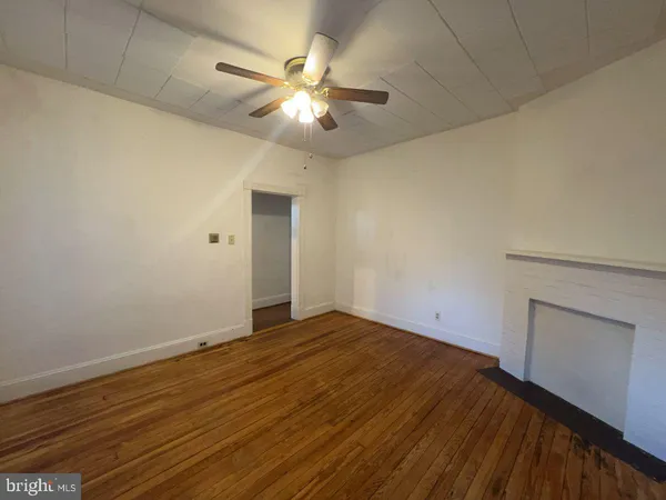 wooden floor in an empty room with a chandelier fan