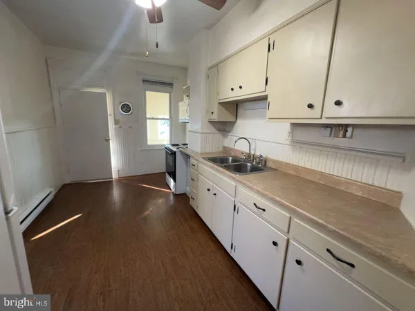 a kitchen with granite countertop a sink a stove and cabinets
