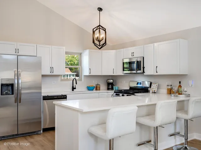 a kitchen with stainless steel appliances granite countertop a sink a stove a refrigerator cabinets and chairs