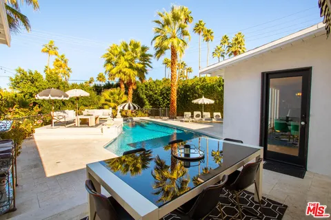 a view of a patio with couches table and chairs potted plants and palm tree