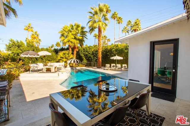 a view of a patio with couches table and chairs potted plants and palm tree