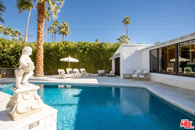 a view of a patio with couches and table and chairs under an umbrella with palm trees