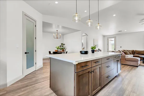 a large white kitchen with a large island oven a sink with wooden floor