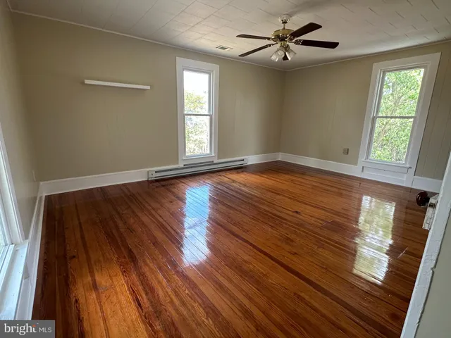 a view of an empty room with window and wooden floor