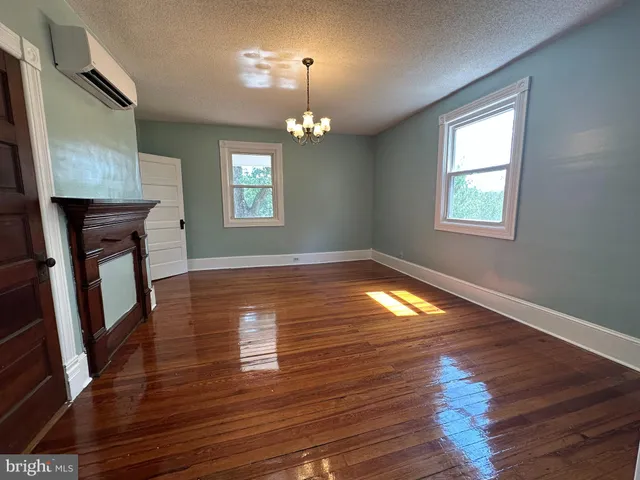 a view of a room with wooden floor fireplace and windows