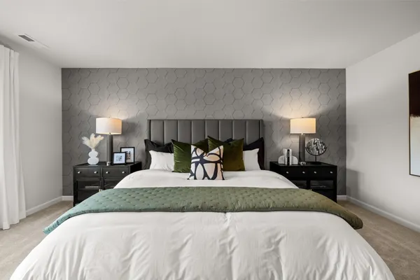 a bedroom with a bed and a lamp on dresser