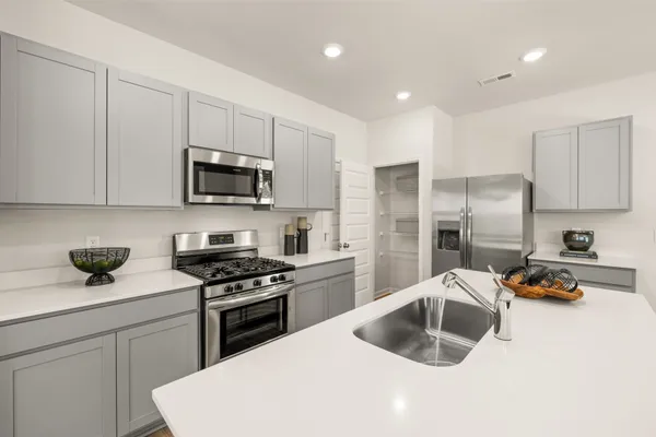 a kitchen with stainless steel appliances granite countertop a sink stove refrigerator and cabinets