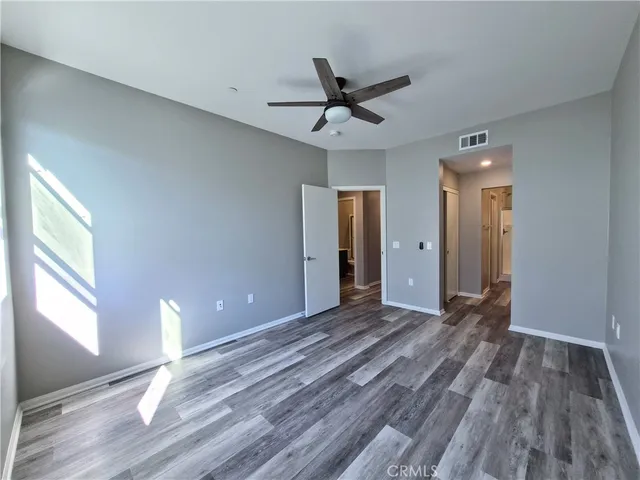 a view of a hallway with wooden floor and a bathroom
