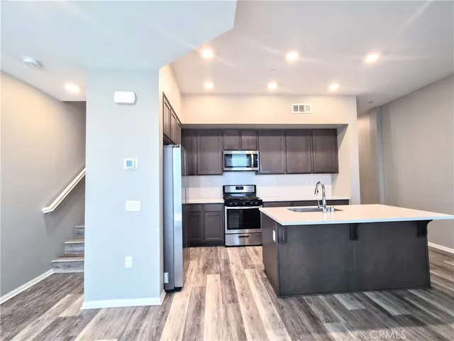 a large kitchen with stainless steel appliances a large counter top a stove and a refrigerator