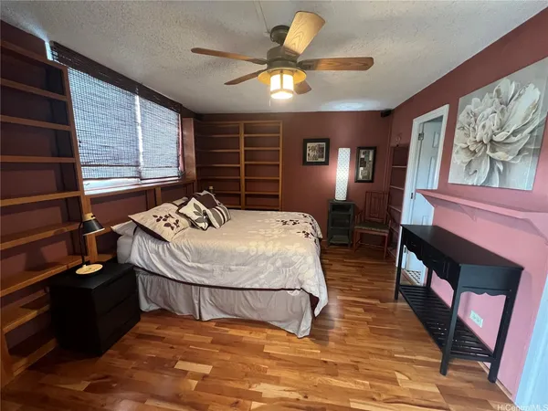 a bedroom with a bed a dresser and wooden floor