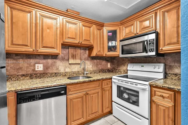 a kitchen with granite countertop cabinets stainless steel appliances and a window