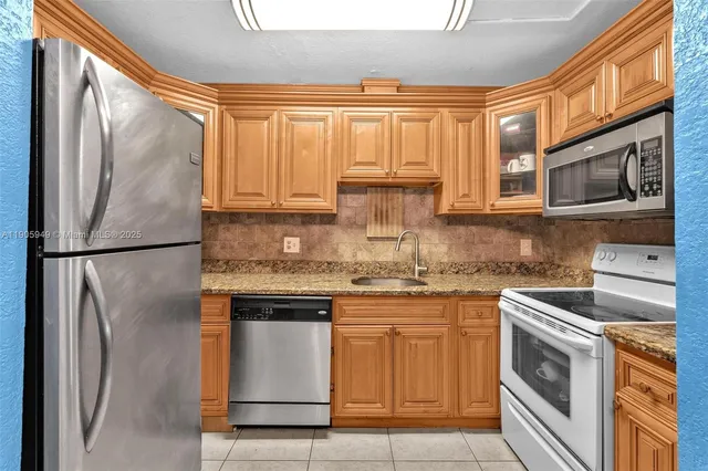 a kitchen with stainless steel appliances granite countertop a refrigerator a stove a sink and a microwave