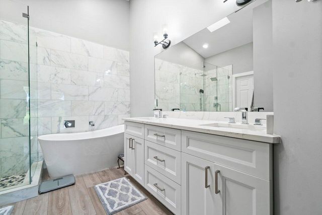 a spacious bathroom with a double vanity sink mirror and a bathtub