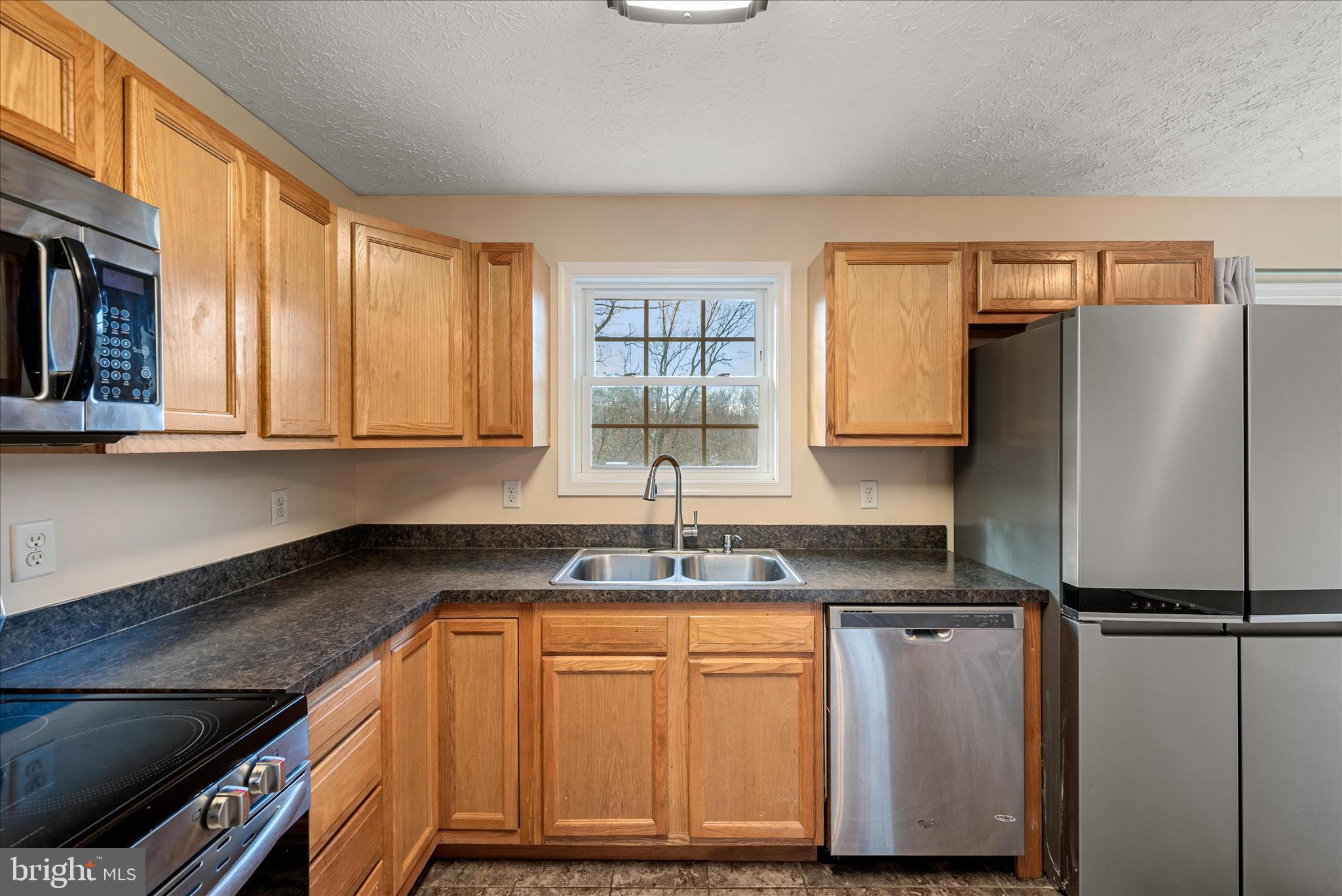 181 Brook View Road Front Royal, VA 22630 - Photo 9 of 47 a kitchen with granite countertop a refrigerator a sink and wooden cabinets