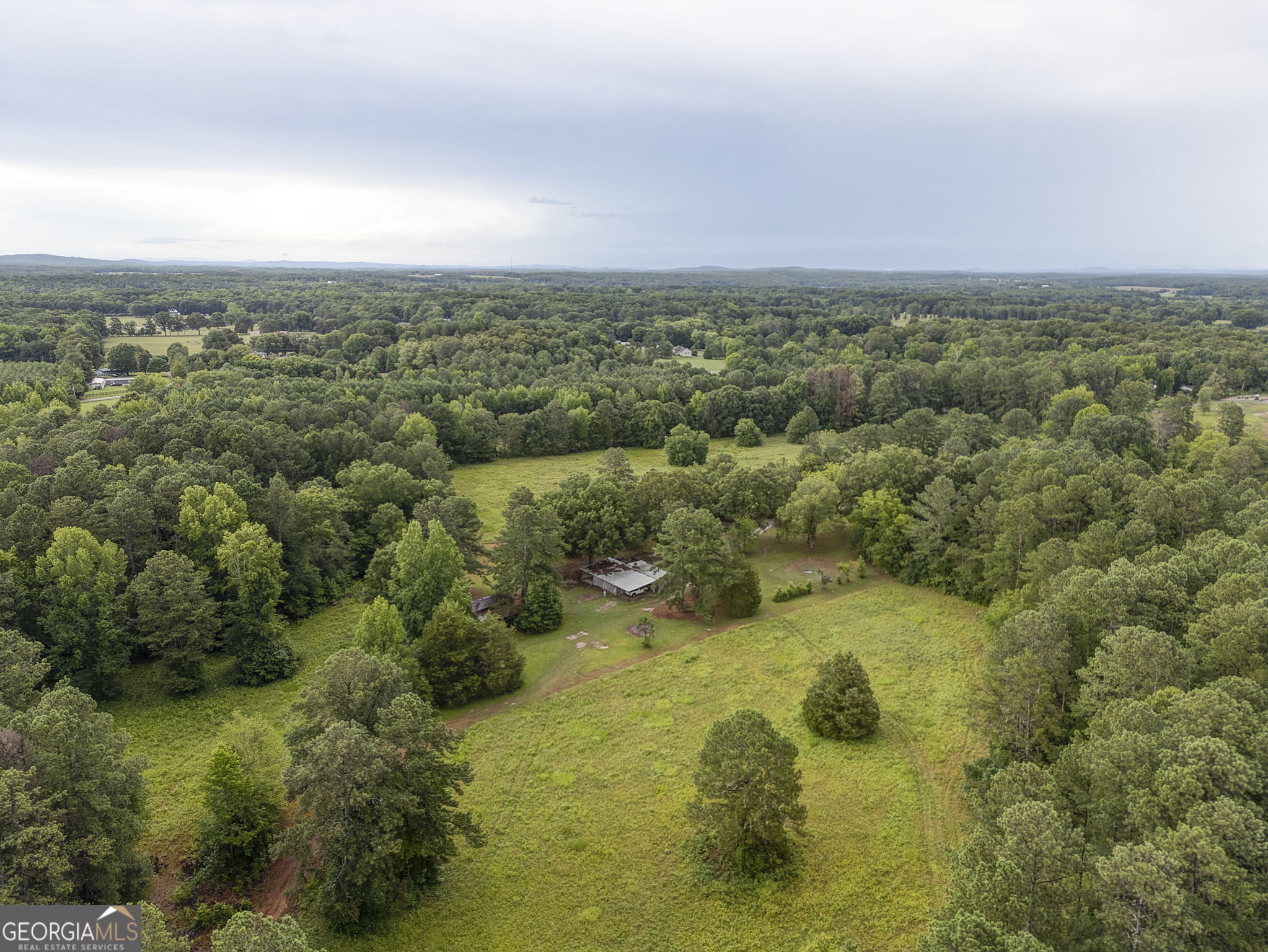 an aerial view of residential houses with outdoor space and trees