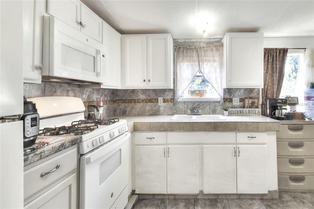 730 McClellan Road Frostproof, FL 33843 - Photo 18 of 50 a kitchen with white cabinets and white appliances