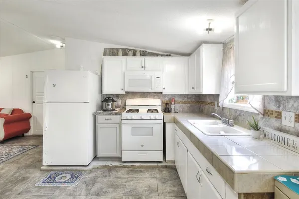 a kitchen with a sink a stove a refrigerator and white cabinets