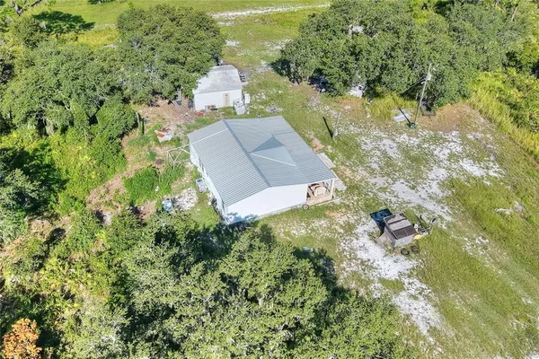 an aerial view of residential house with outdoor space and trees all around