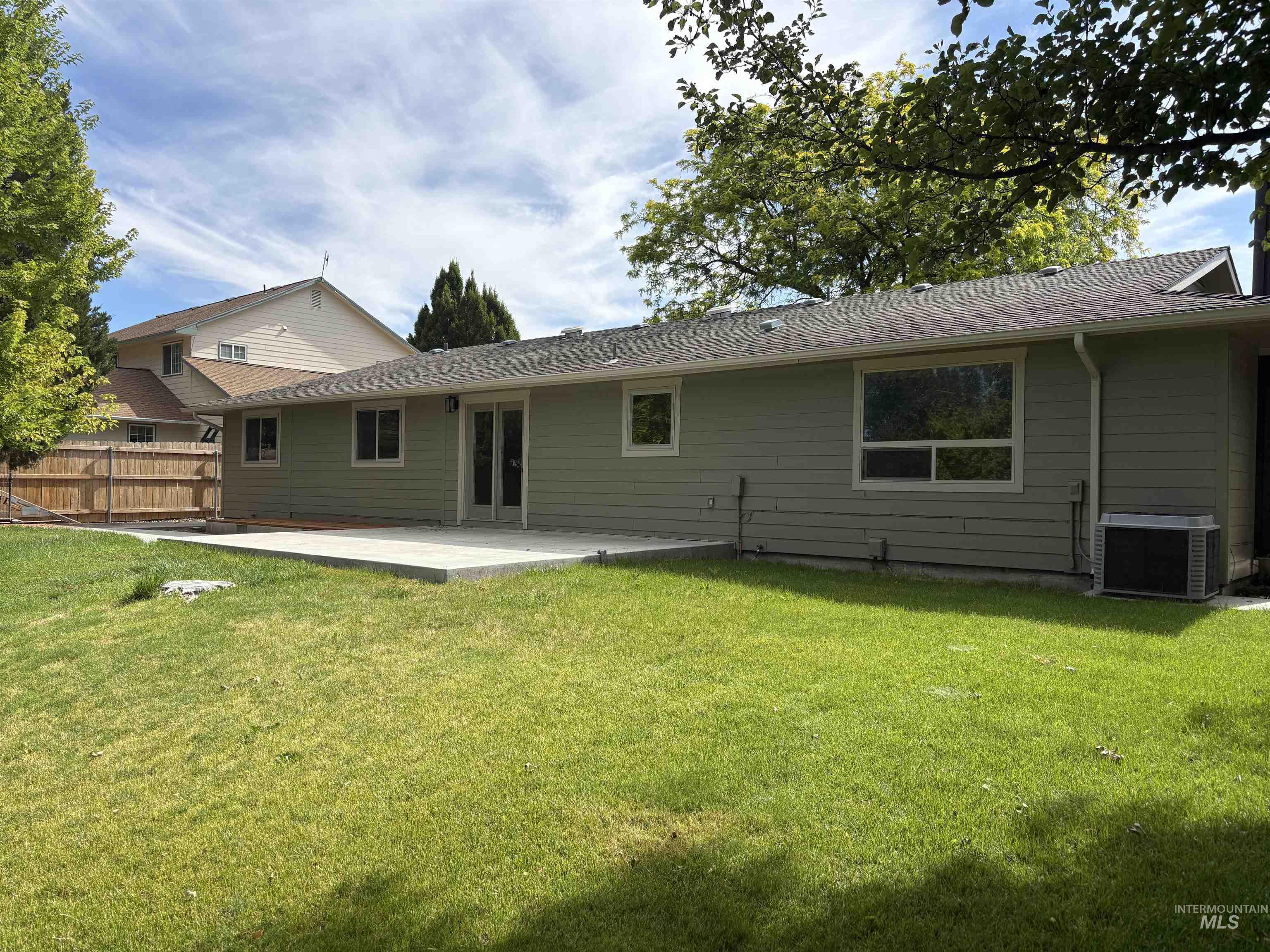 513 Ridge Way Ontario, OR 97914 - Photo 6 of 29 Expansive lawn area featuring a concrete patio, light green siding, multiple windows, and sliding glass doors