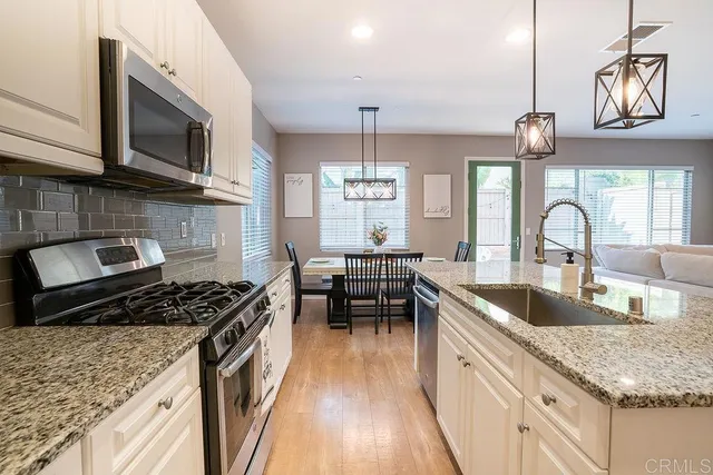 a kitchen with granite countertop a stove a sink and a microwave