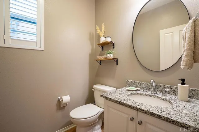 a bathroom with a granite countertop toilet a sink and a mirror