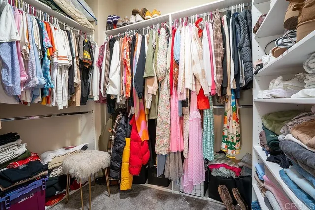 a view of walk in closet with clothes and shoes