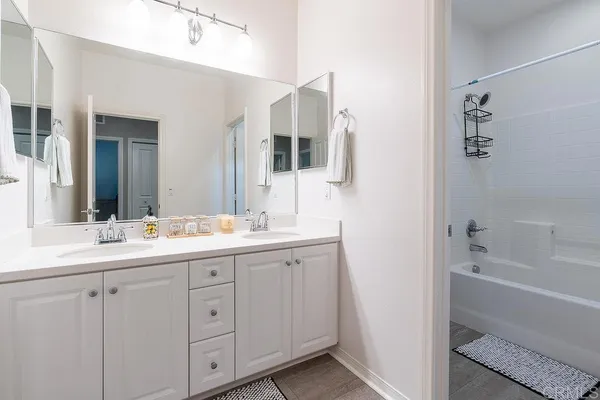 a bathroom with a double vanity sink mirror and bathtub