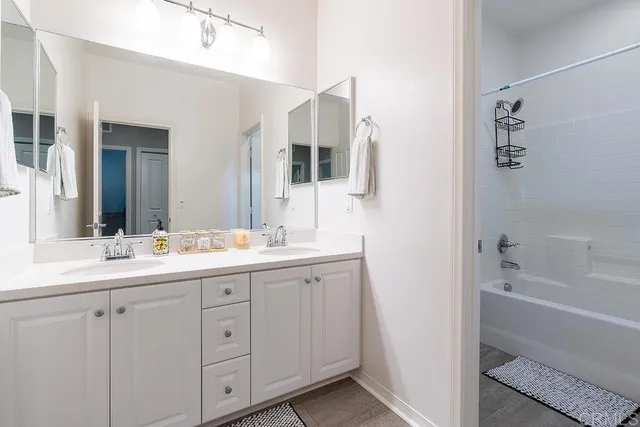 a bathroom with a double vanity sink mirror and bathtub
